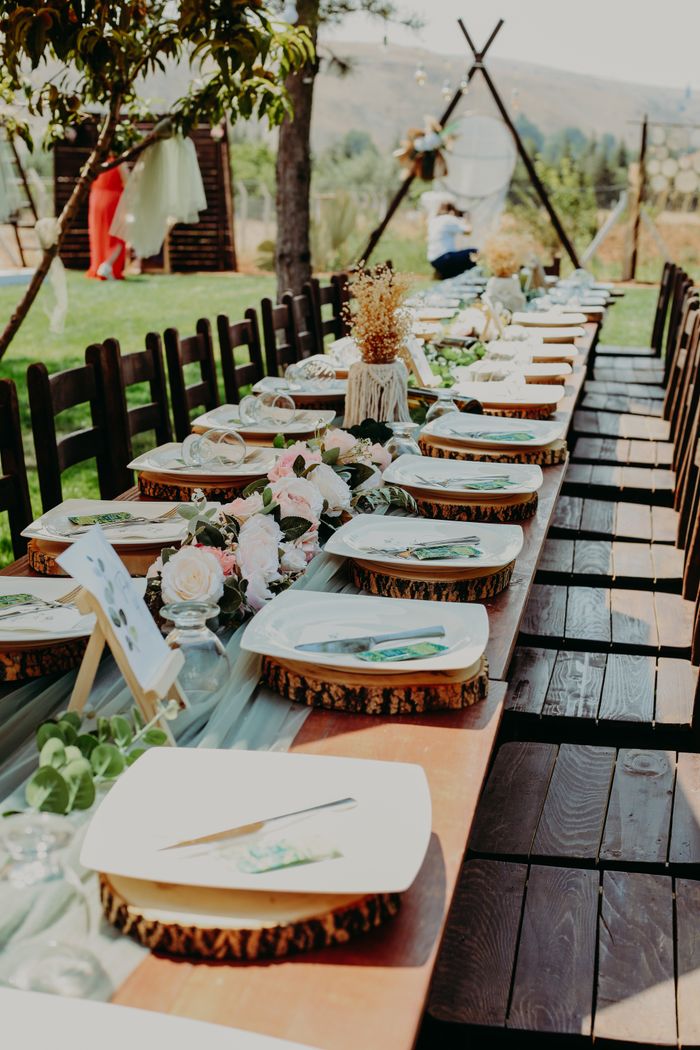 gallery-06 Beautiful rustic table setup for a wedding with wooden decor, plates, and floral arrangements outdoor setting.