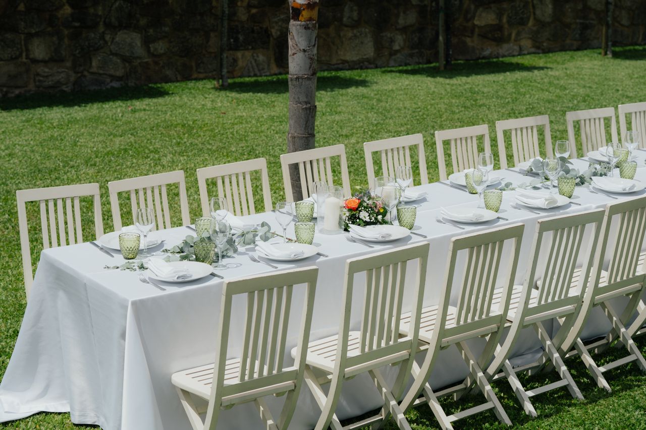gallery-05 Chic outdoor wedding table with white chairs and floral decor on a sunny summer day.