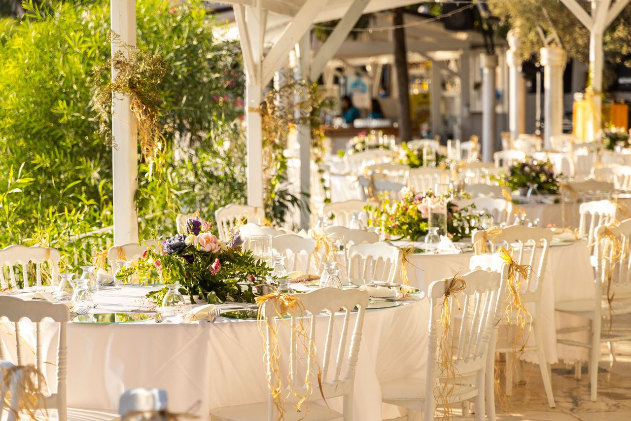 gallery-02 Beautifully arranged outdoor wedding reception with floral centerpieces and white decor.